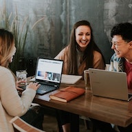 trois personnes avec des ordinateurs rient